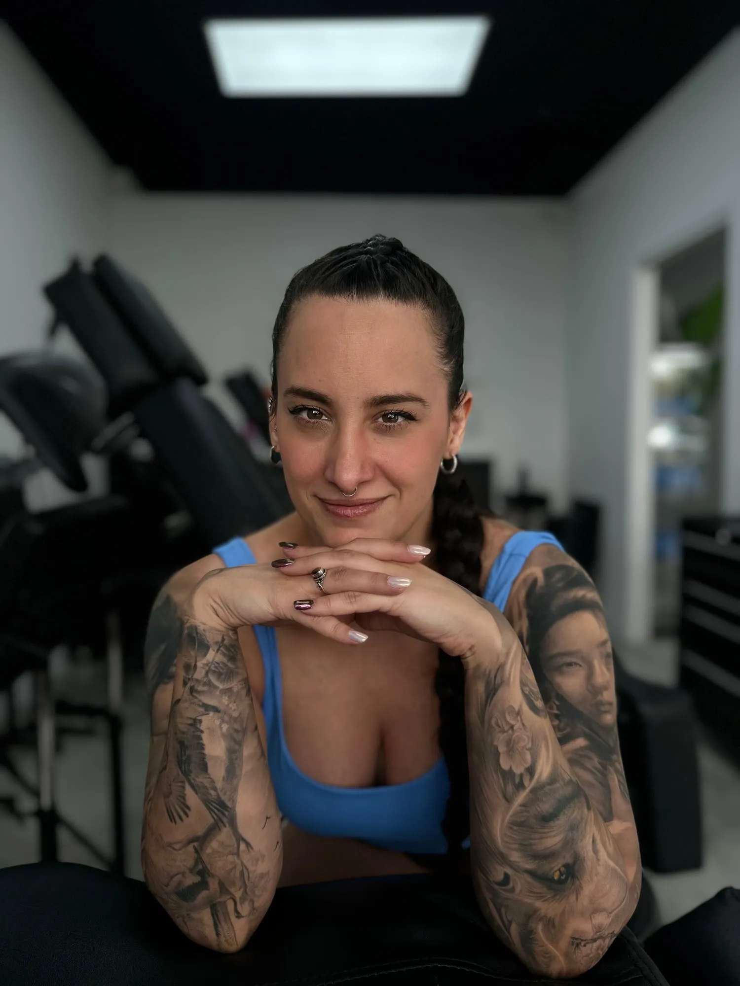 Tiffany, tatuadora en Málaga, sonriendo con los brazos tatuados apoyados bajo la barbilla